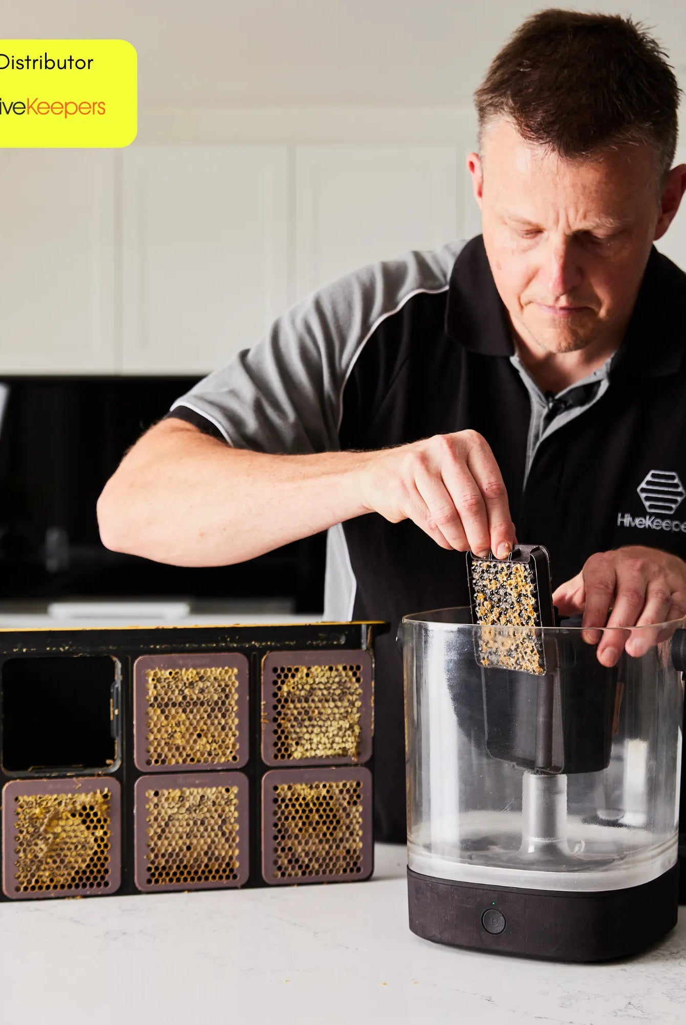 Person loading a honeycomb cassette into the Micro Honey Harvester on a kitchen counter