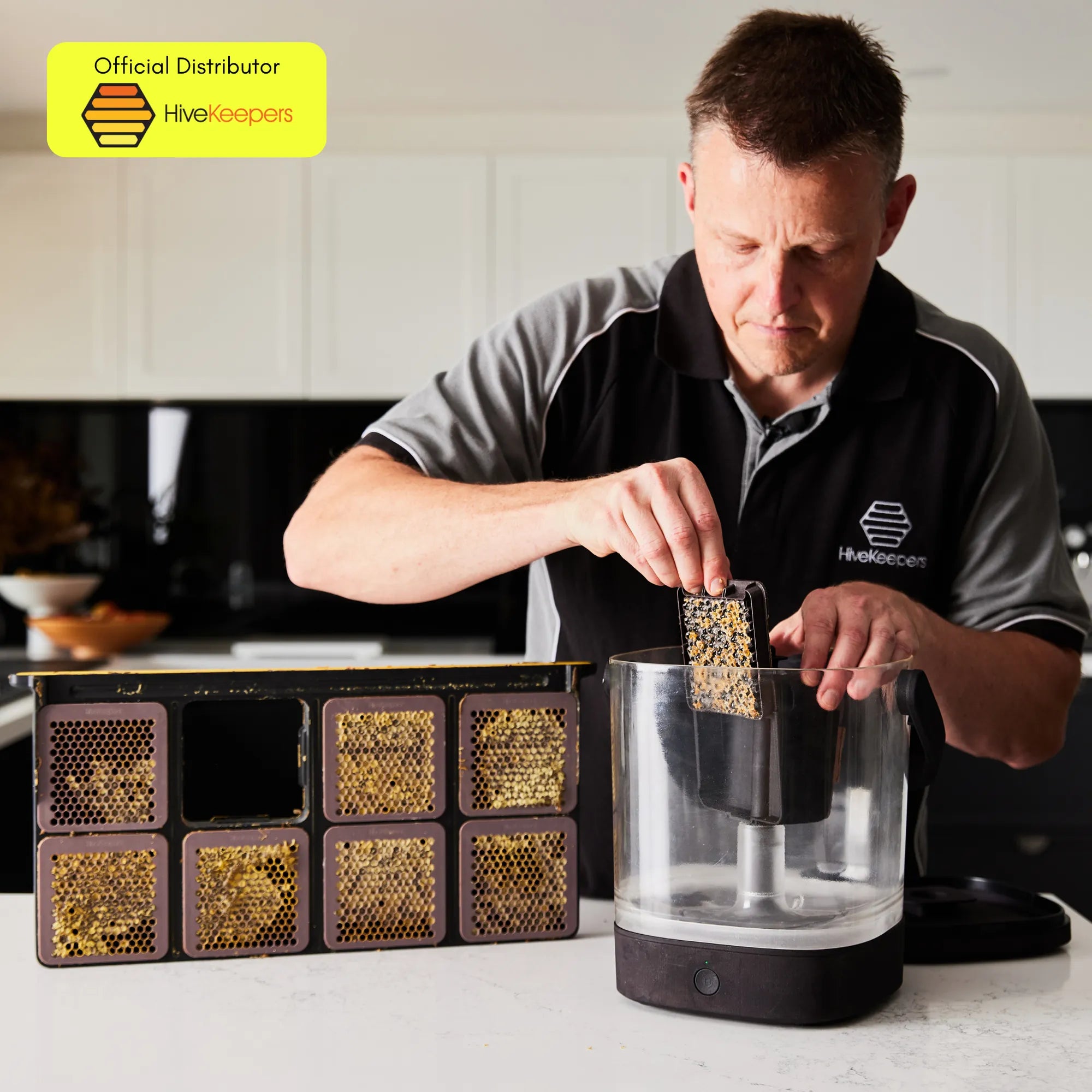 Person loading a honeycomb cassette into the Micro Honey Harvester on a kitchen counter